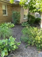 A brick house with a lot of plants in front of it