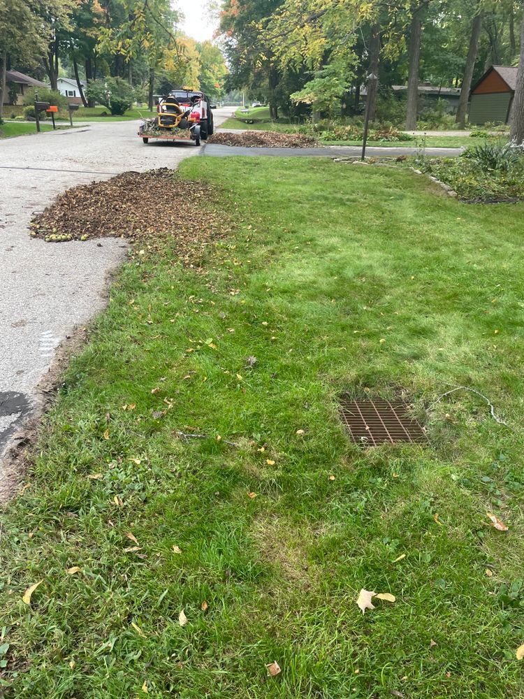 A lawn mower is cutting grass next to a road