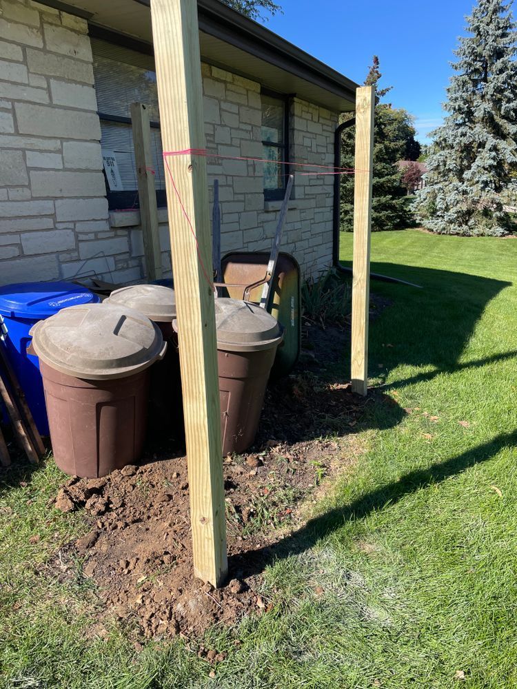 A wooden post is sitting in the dirt in front of a brick house