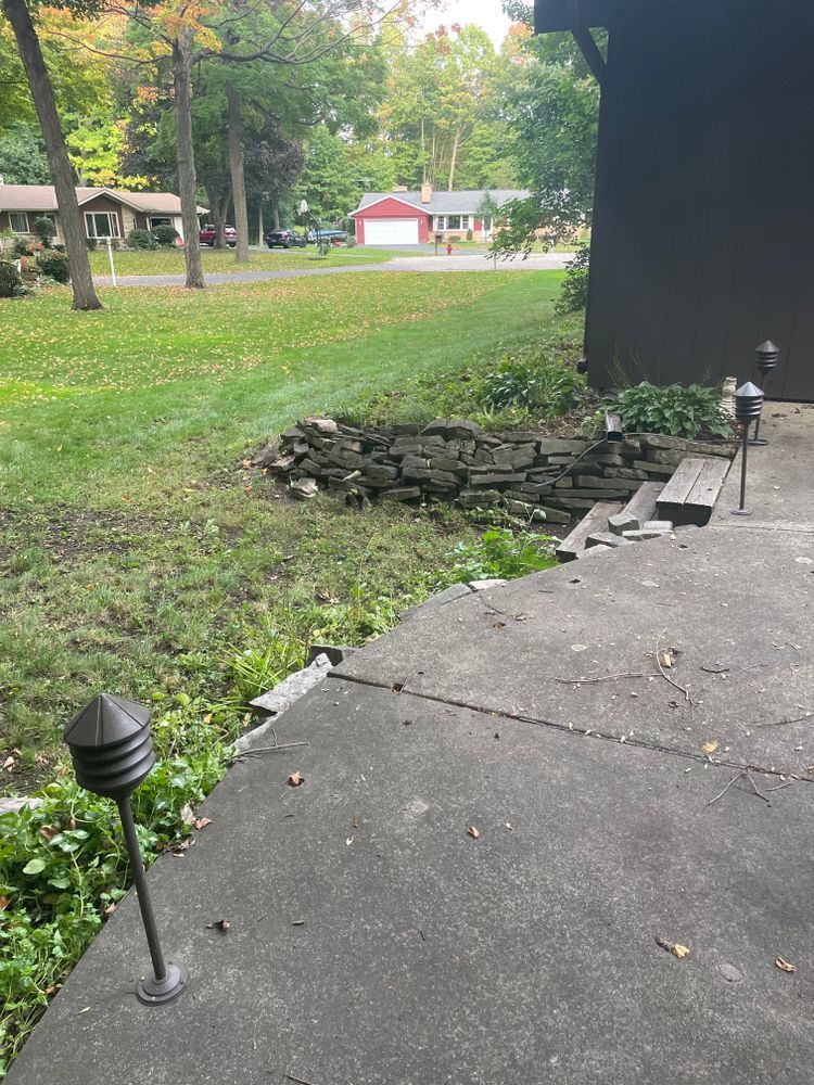 A concrete walkway leading to a house with a red barn in the background