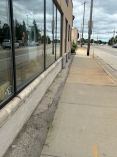 A sidewalk next to a building with a lot of windows