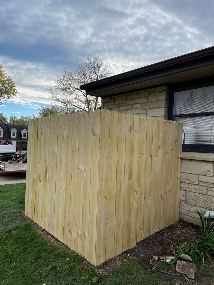 A wooden fence is sitting in front of a brick house