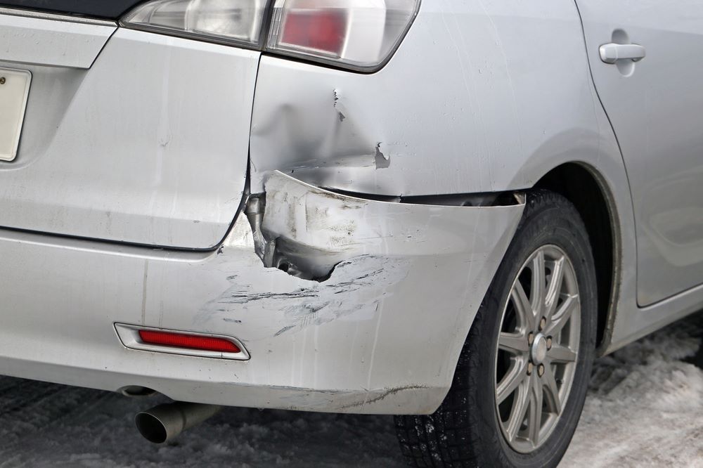 A Silver Car With a Damaged Bumper is Parked in the Snow — Smash Repairs In Tuncurry, NSW