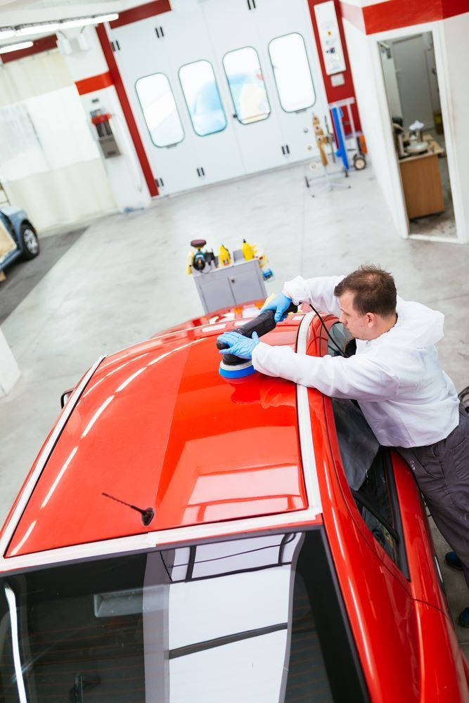 A Man is Polishing the Roof of a Red Car — Smash Repairs In Hallidays Point, NSW