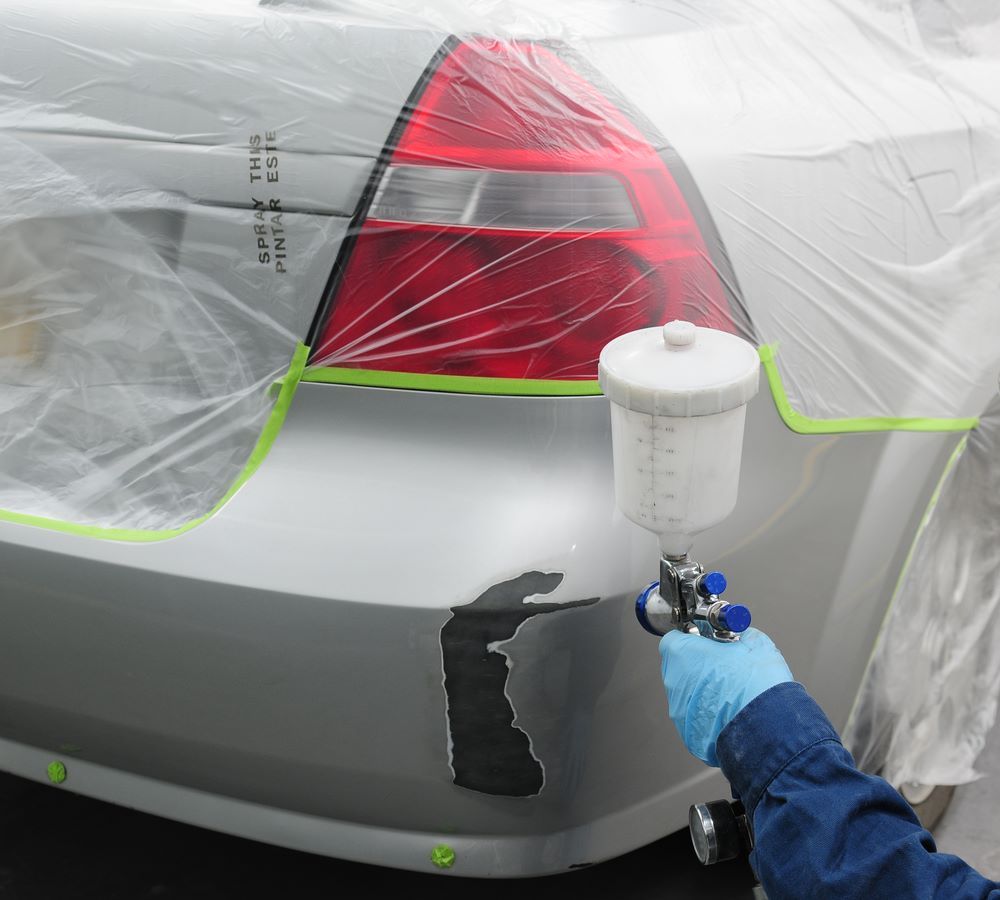 A Person is Spraying Paint on a Silver Car — Smash Repairs In Bulahdelah, NSW