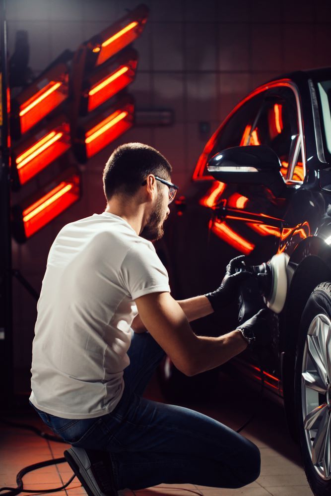 A Man is Polishing a Car in a Garage — Smash Repairs In Gloucester, NSW
