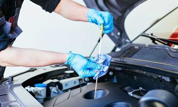 A man is checking the oil level of a car with a dipstick.