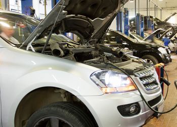 A car with its hood up is being charged in a garage.