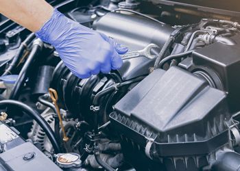 A person is working on a car engine with a wrench.