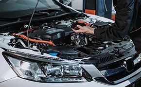 A man is working on the engine of a car with the hood open.