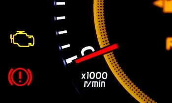 Dashboard with illuminated warning lights: engine, brake, and tachometer at approximately 1500 rpm.