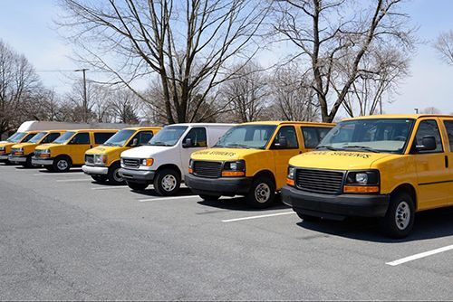 A row of yellow and white vans are parked in a parking lot.