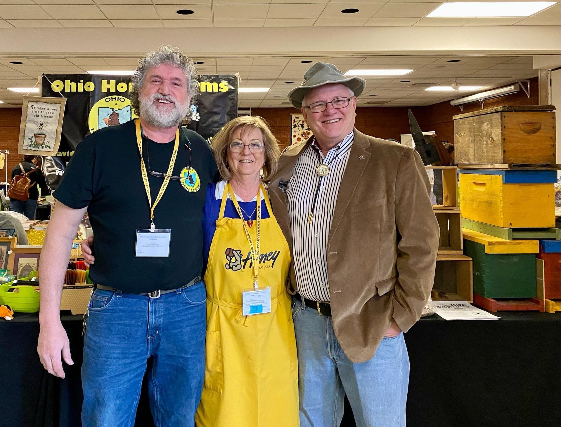 Three people posing for a picture in front of a sign that says ohio honey