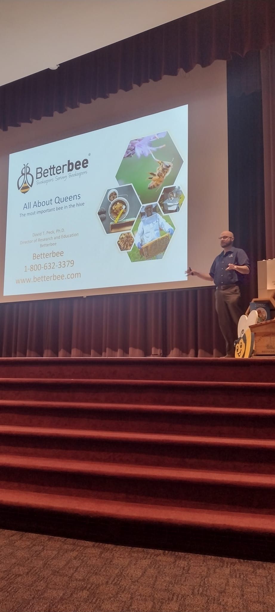 A man is giving a presentation on a stage in front of a large screen.