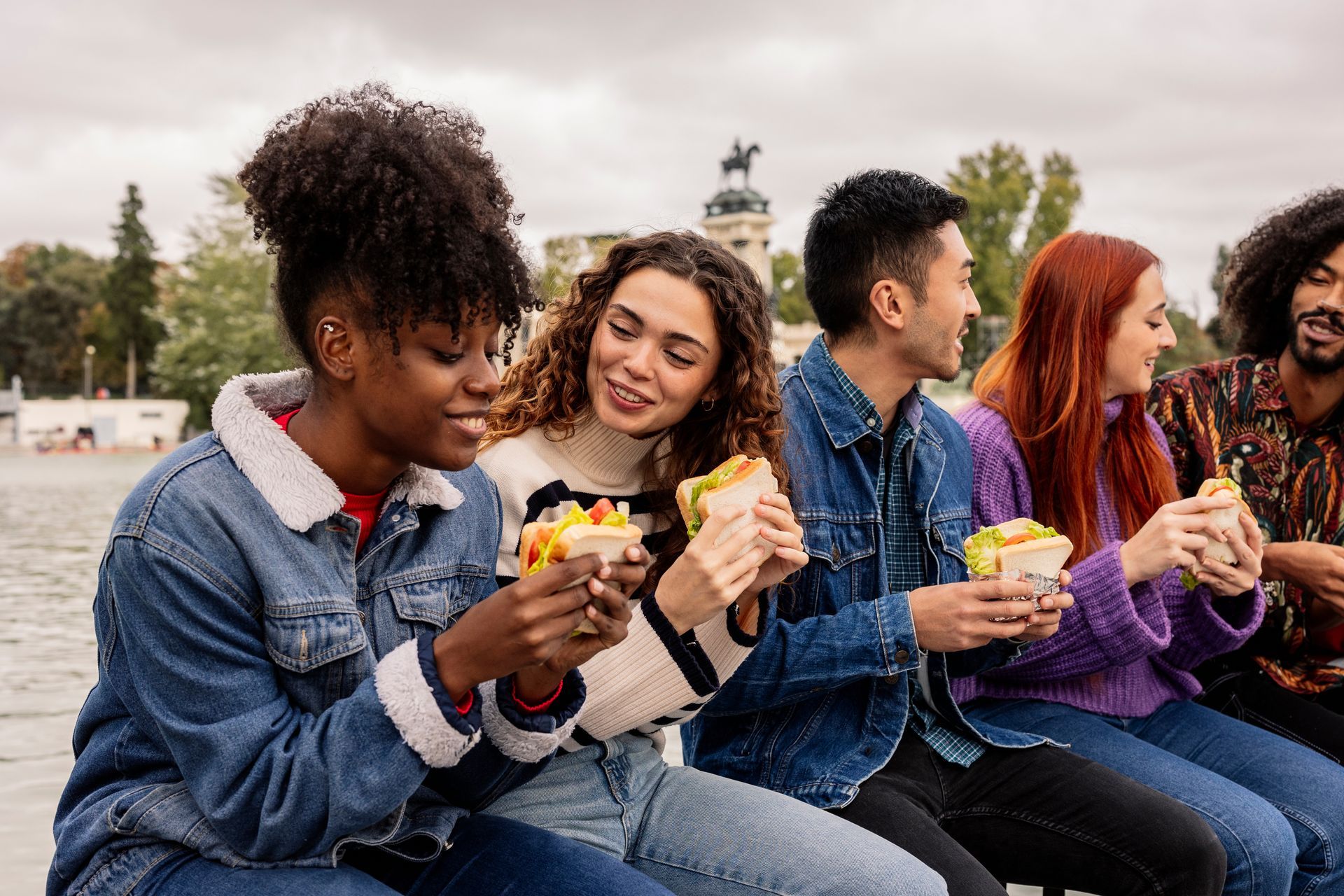 Un groupe de personnes mangeant en terrasse, souriantes, assises.