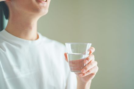 Une personne prend une boisson dans un distributeur automatique, à l'intérieur. Elle tient une canette bleue et tend la main vers l'intérieur de la machine.