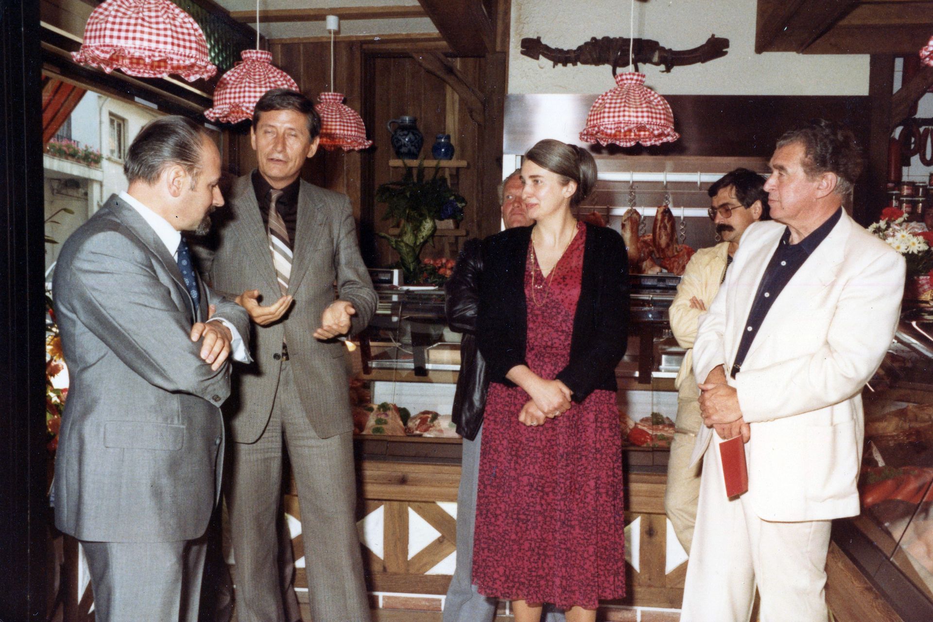 Quatre personnes debout, en pleine conversation, dans un intérieur rustique 
