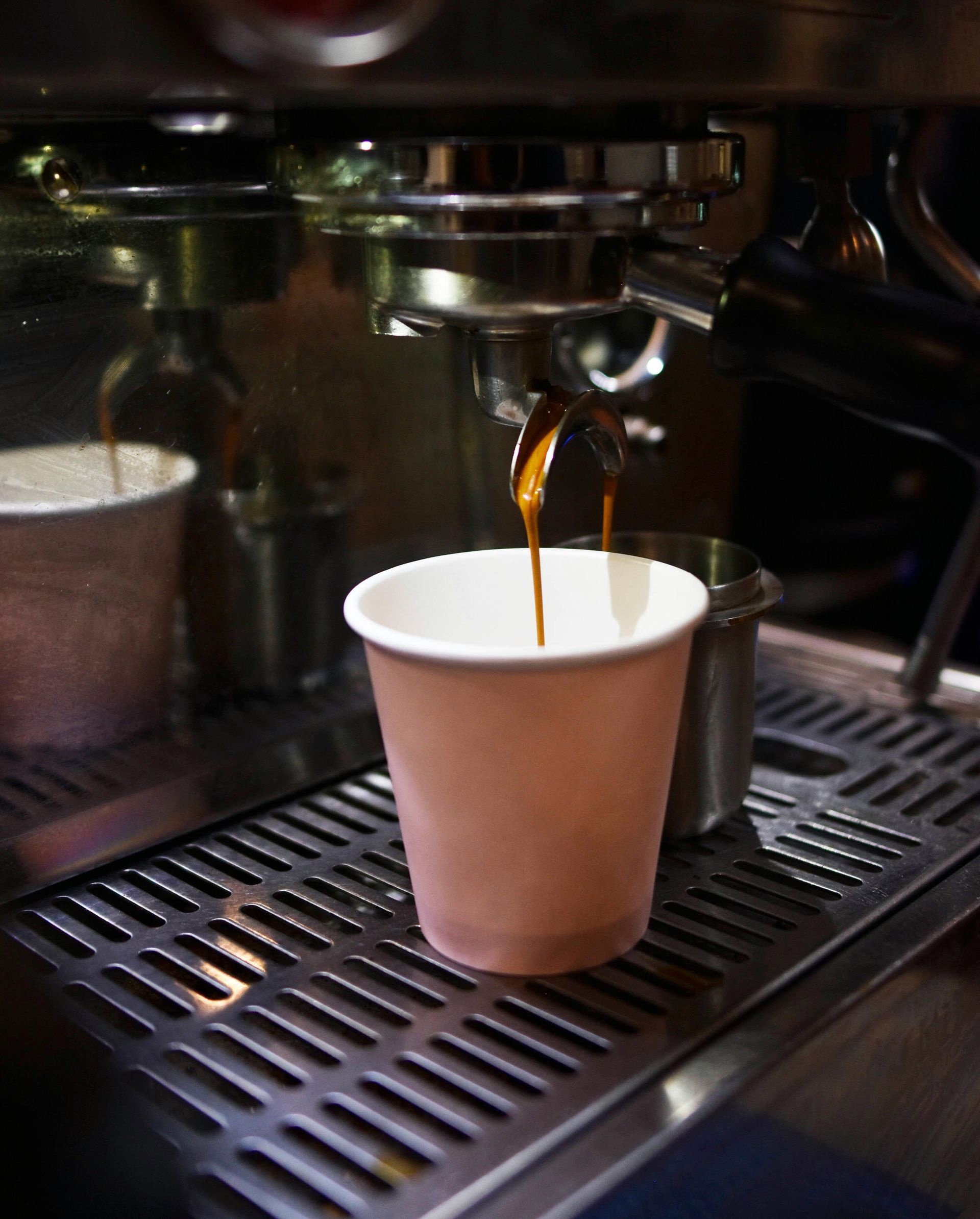 Machine à expresso versant du café dans un gobelet en papier.