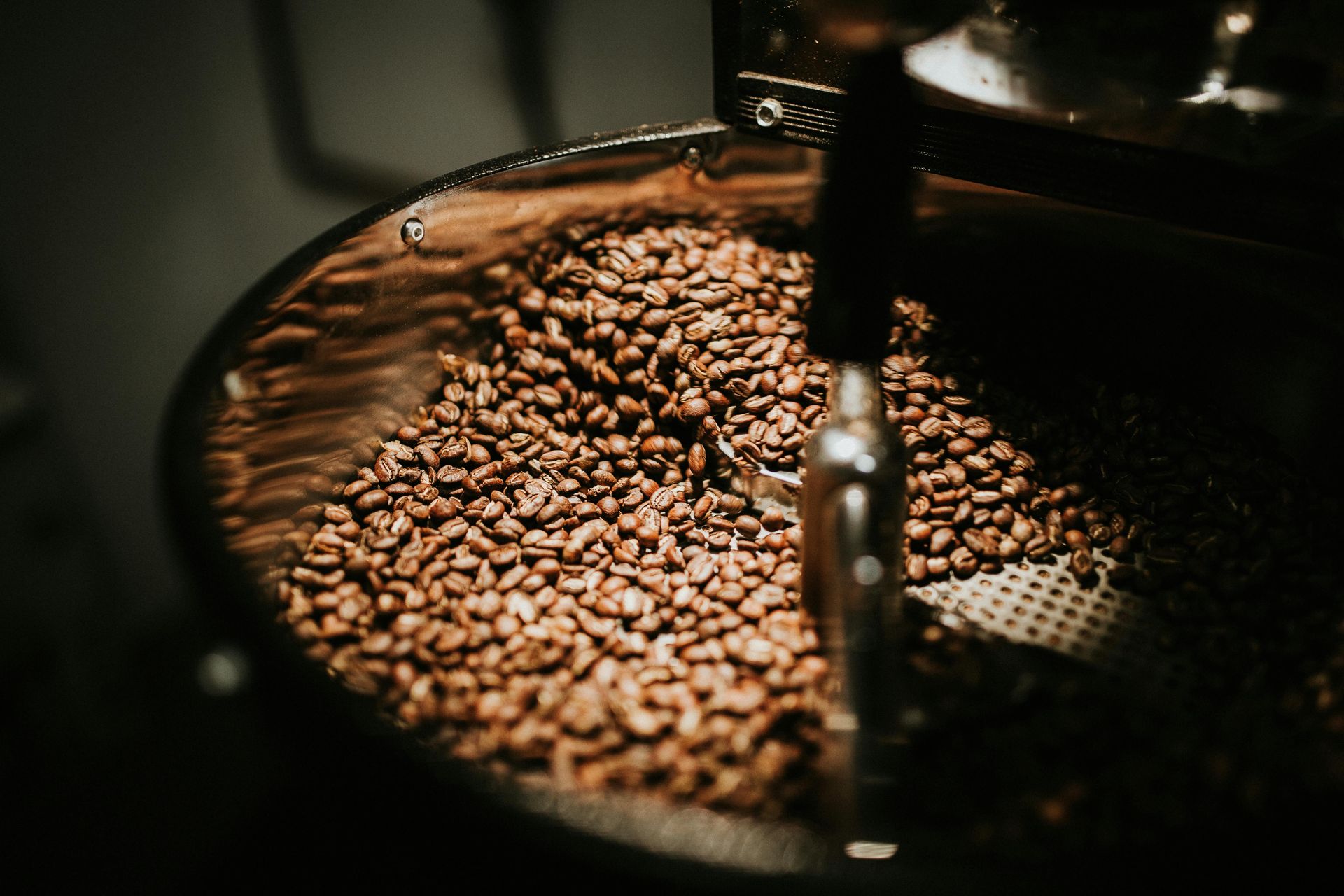 Des grains de café torréfiés tourbillonnent à l'intérieur d'un torréfacteur à tambour.