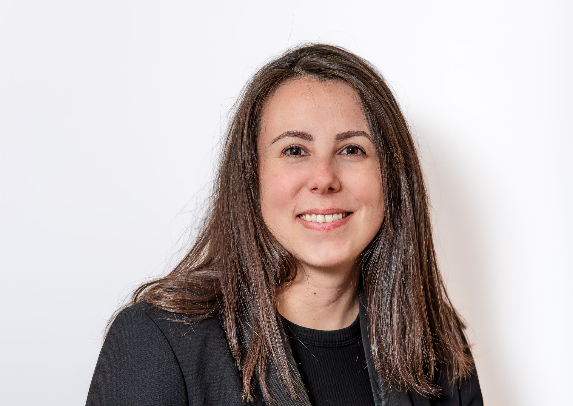 Portrait d'une femme souriante aux longs cheveux bruns sur fond clair