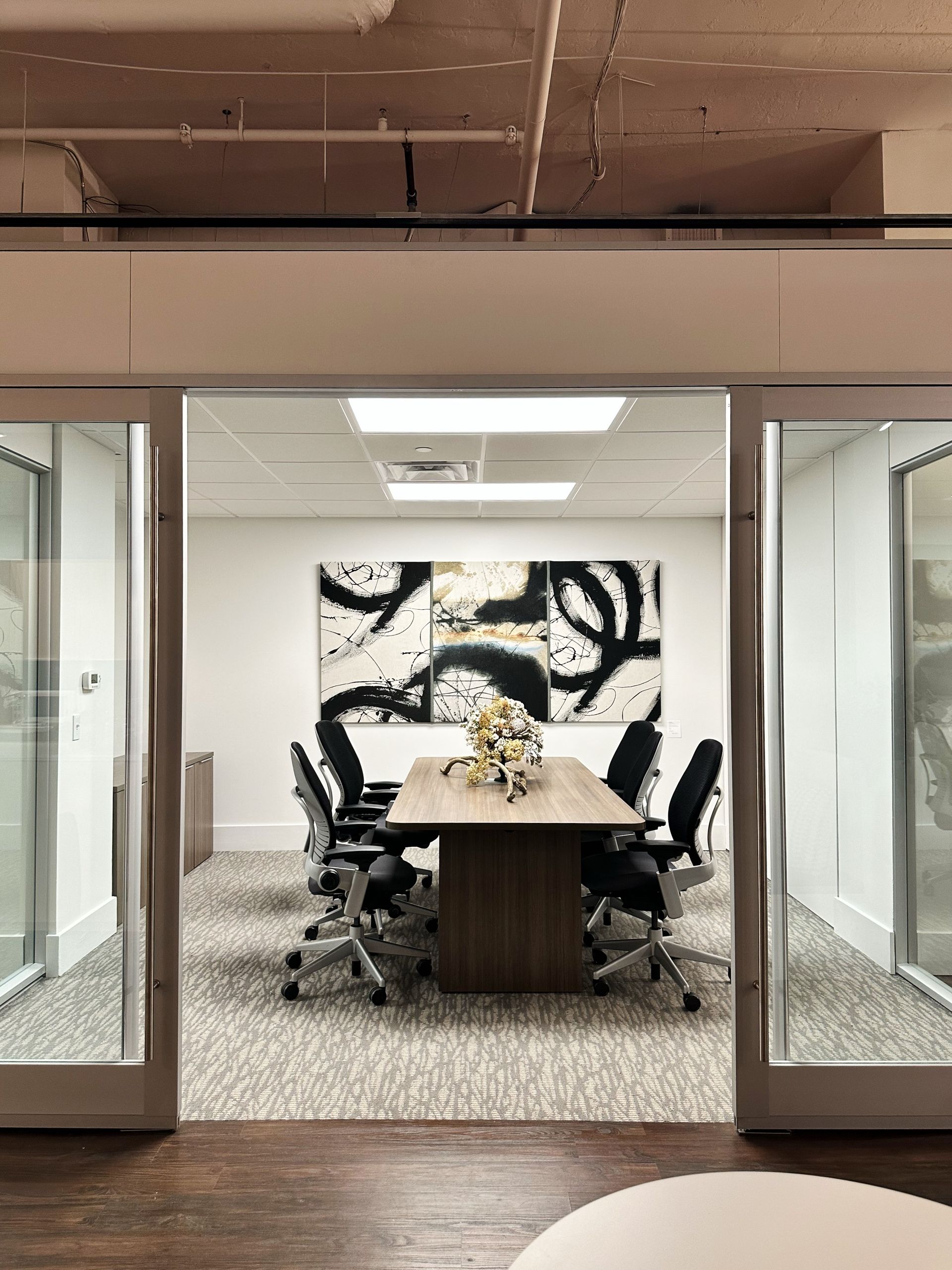 A conference room with a table and chairs and a painting on the wall.