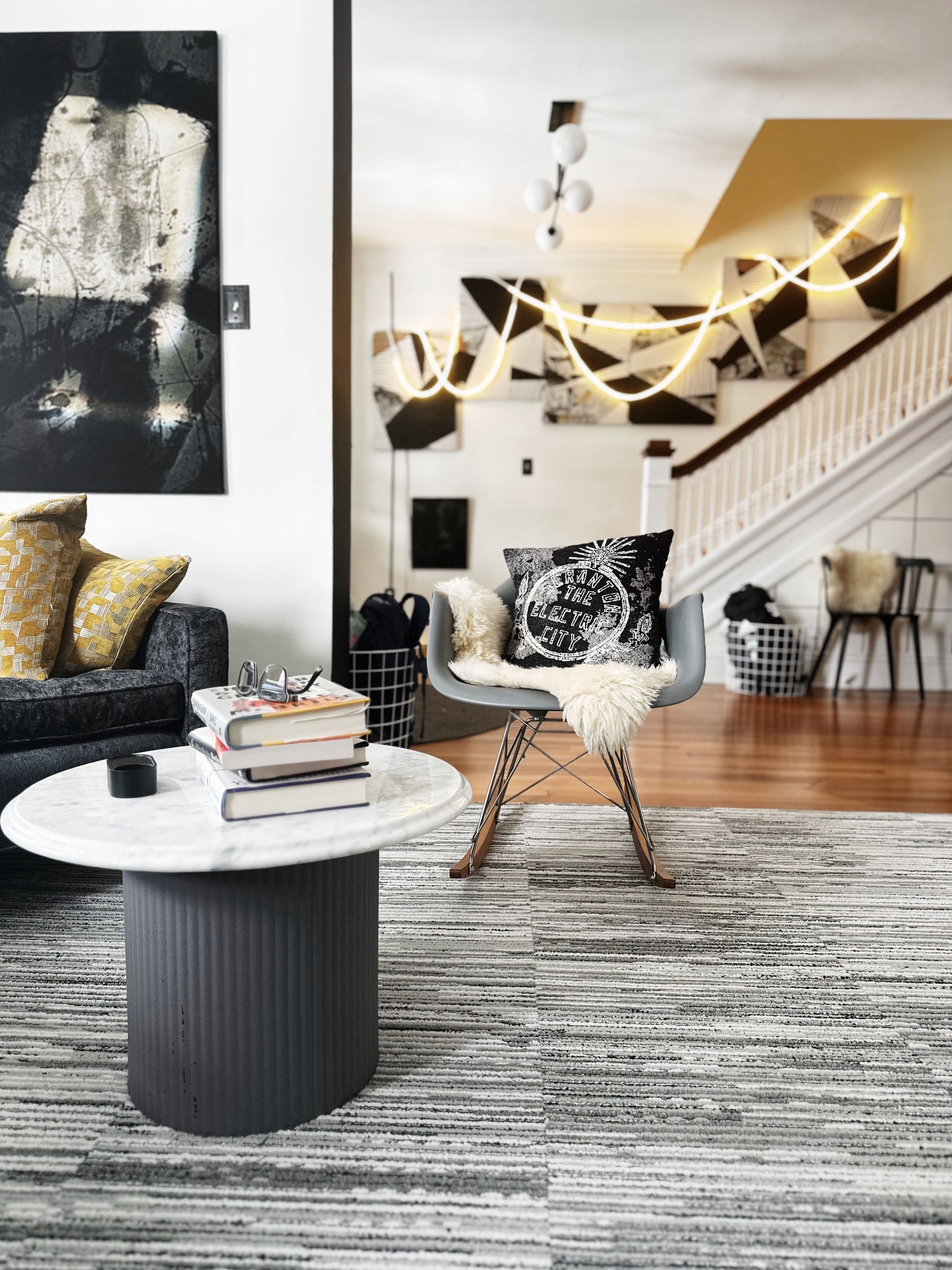 A living room with a rocking chair , couch , coffee table and rug.