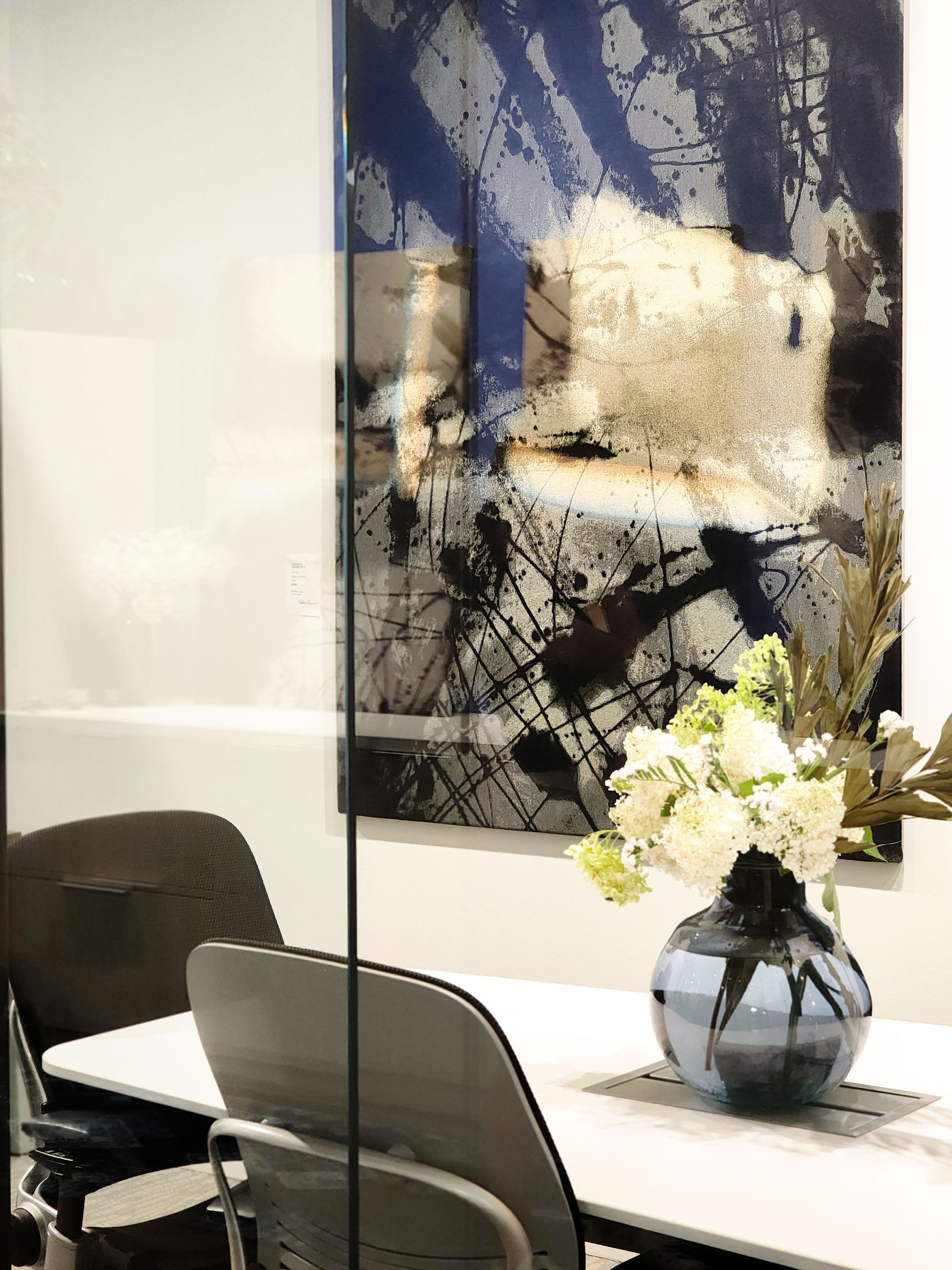 A vase of flowers is sitting on a table in front of a painting.