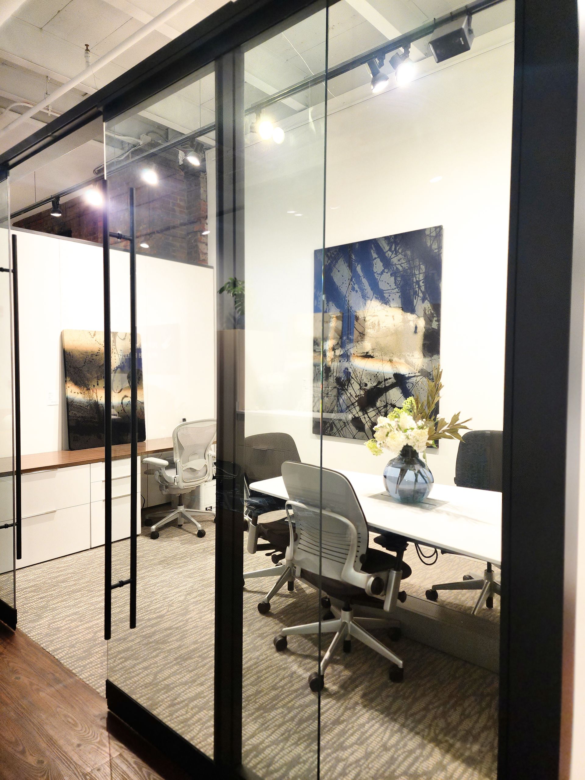A conference room with a glass wall and a table and chairs.