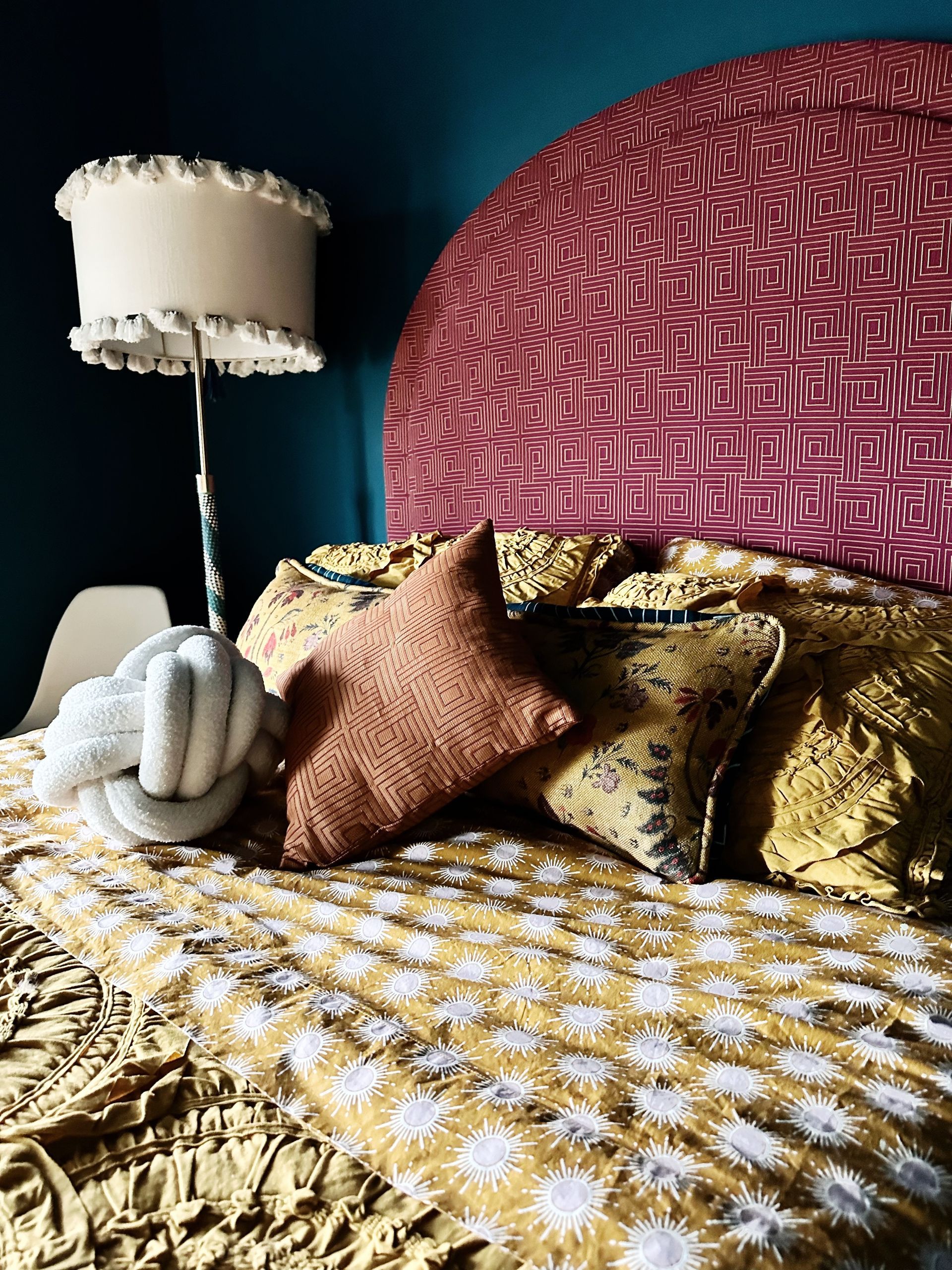 A bed with a lamp and pillows on it in a bedroom.