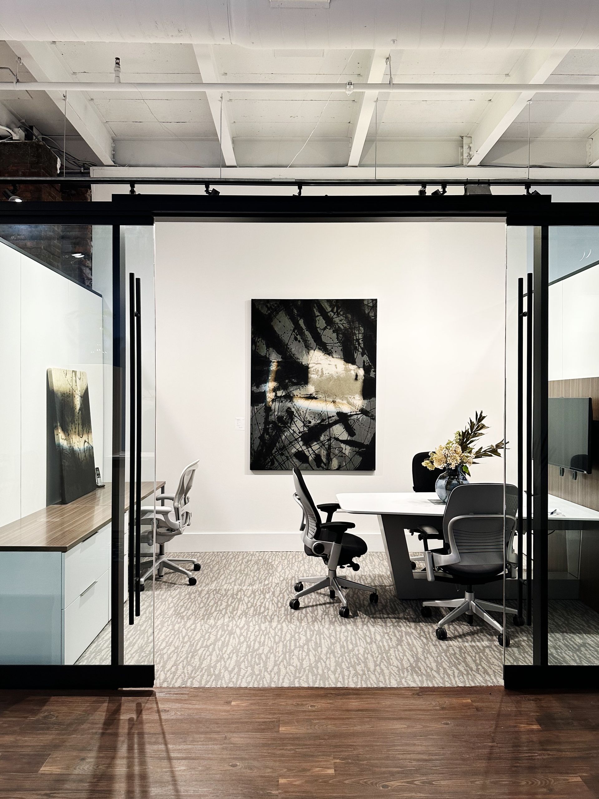 A conference room with a table and chairs and a painting on the wall.
