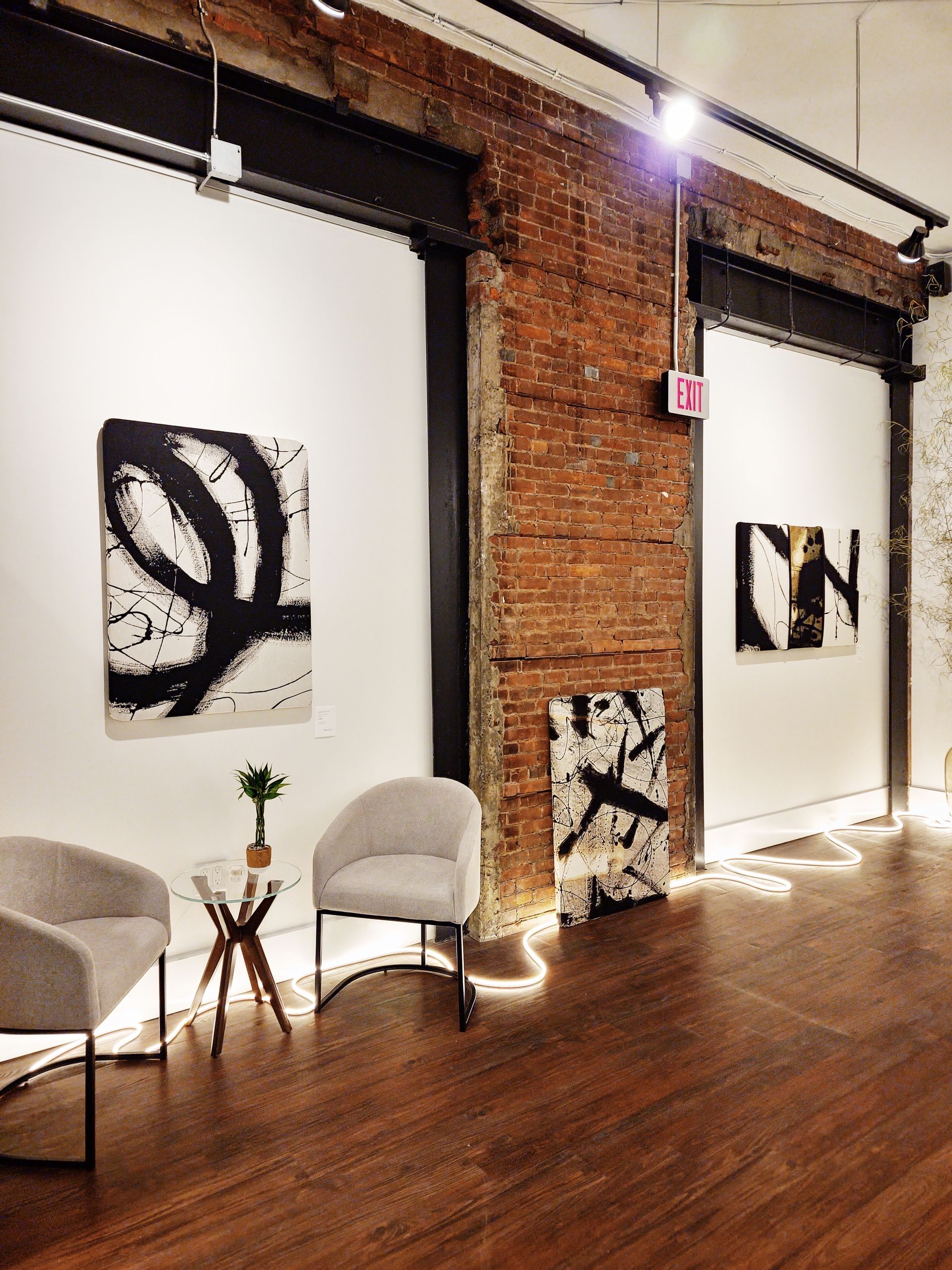 A room with two chairs and a table with paintings on the wall