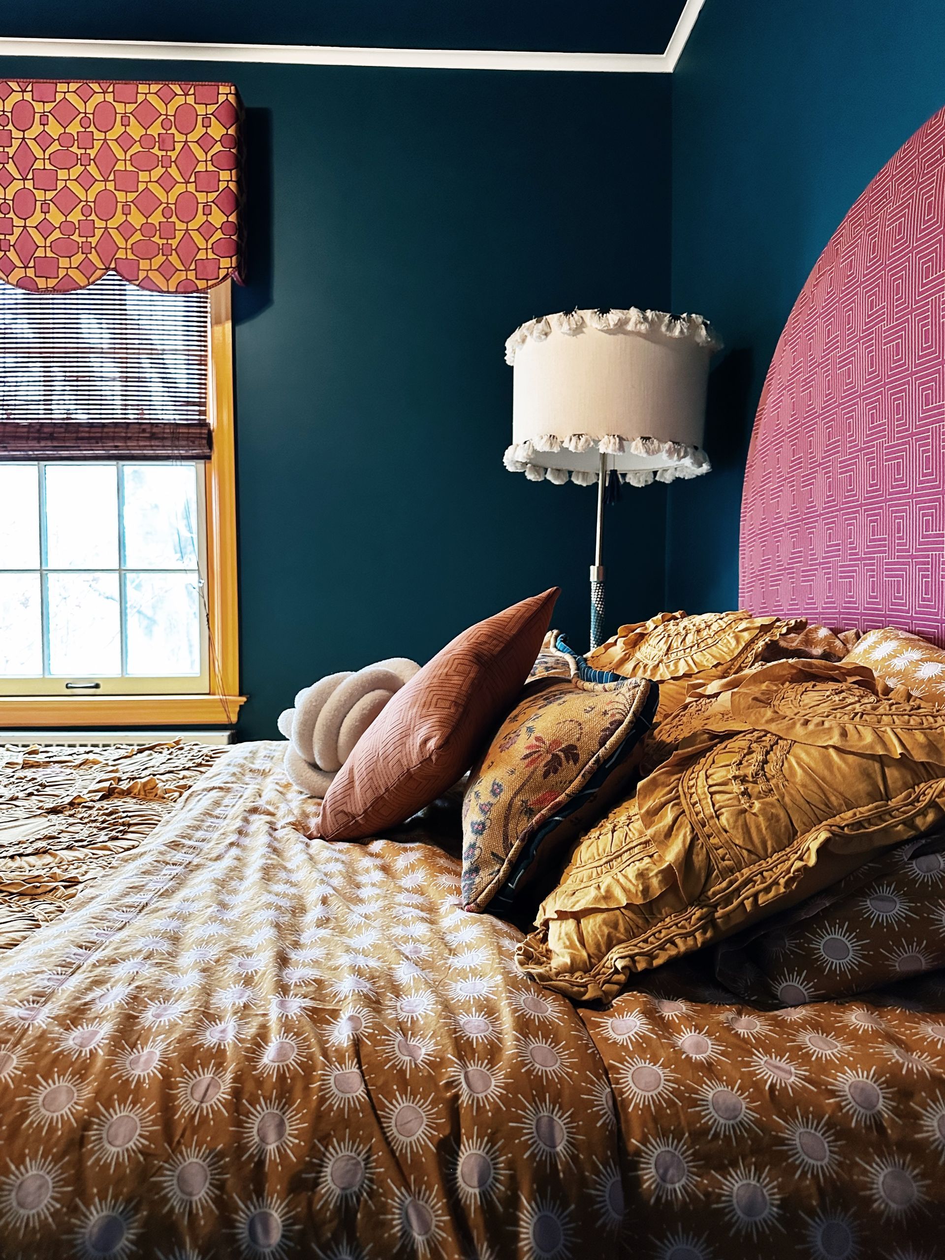 A bedroom with a bed a lamp and a window