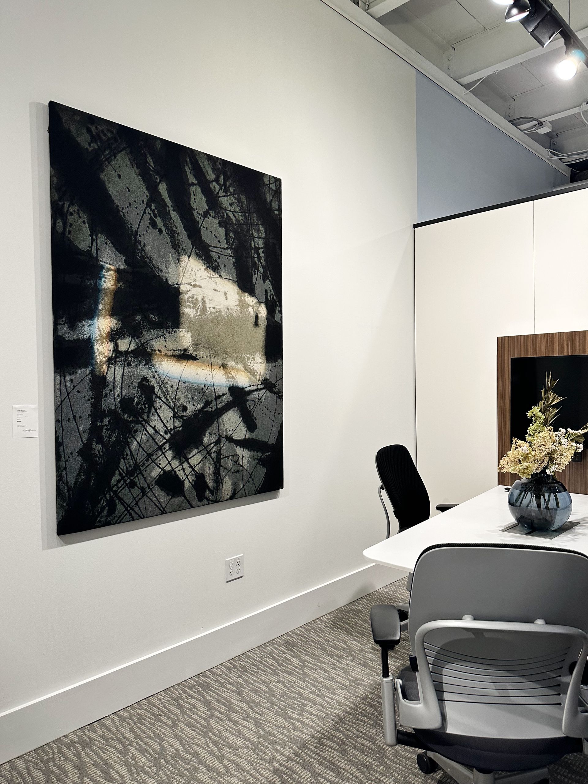 A room with a table and chairs and a large painting on the wall.