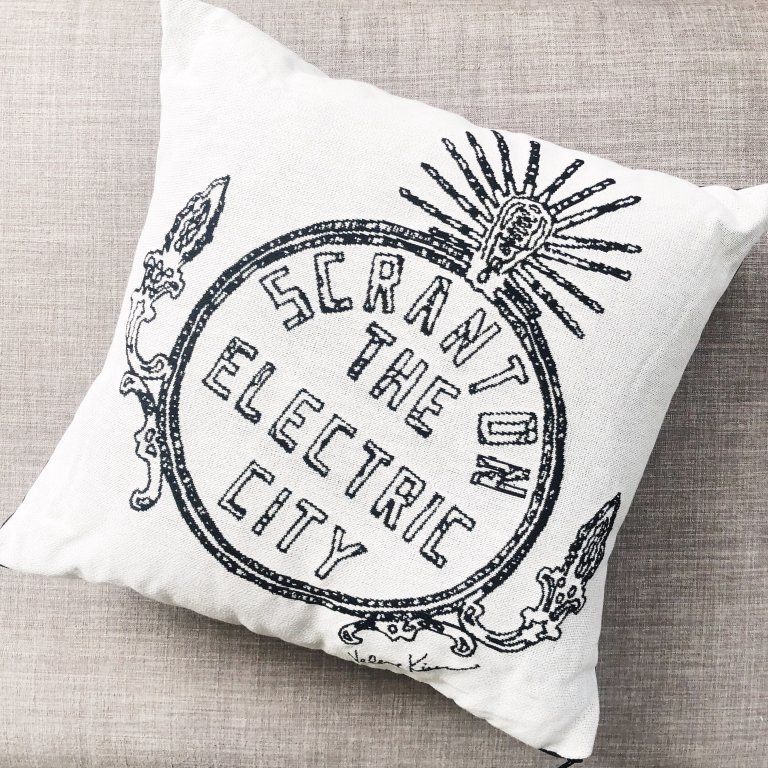 A pillow that says scranton the electric city on it