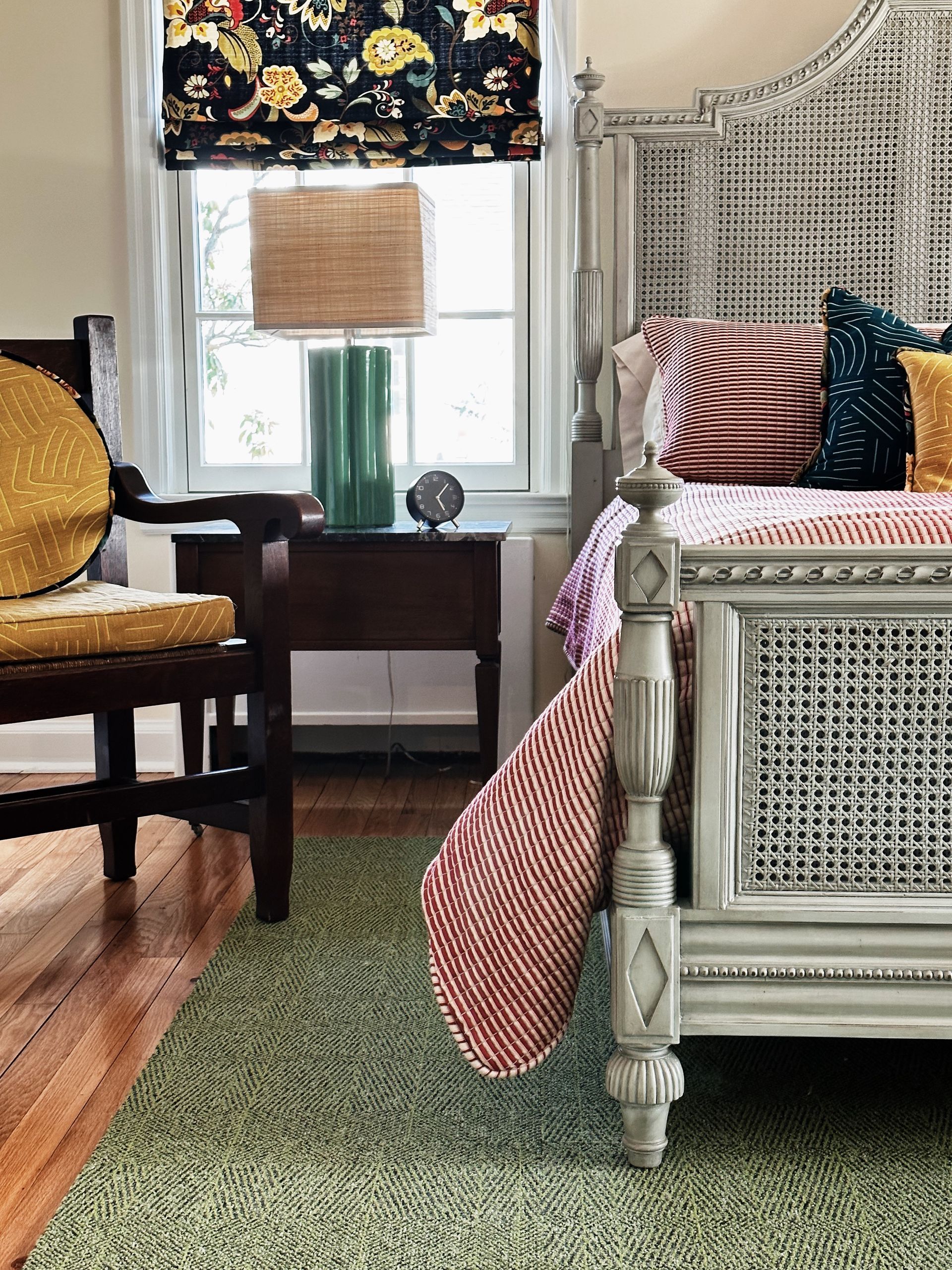 A bedroom with a bed , chair , nightstand and lamp.