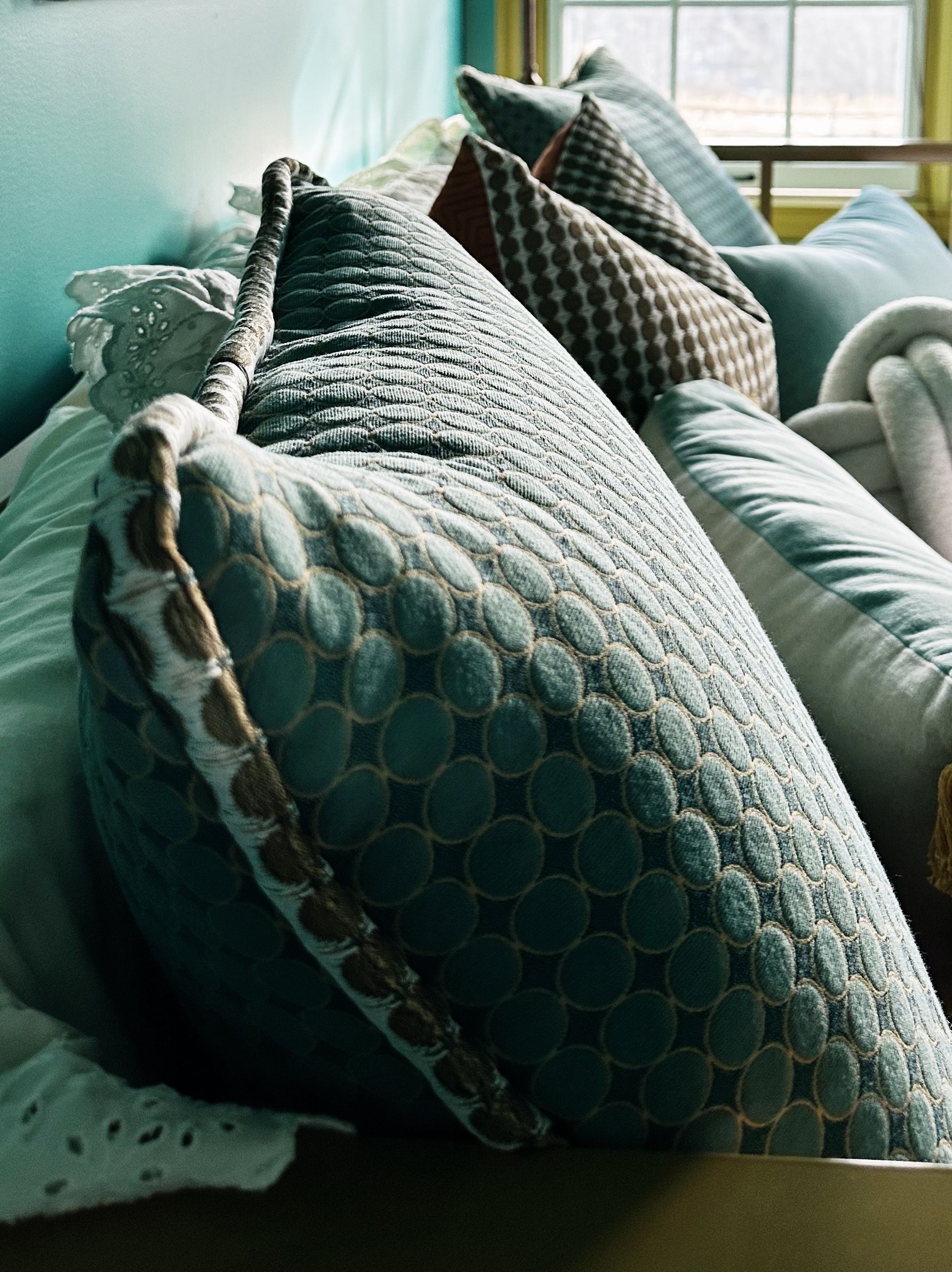 A bunch of pillows are on a couch in front of a window