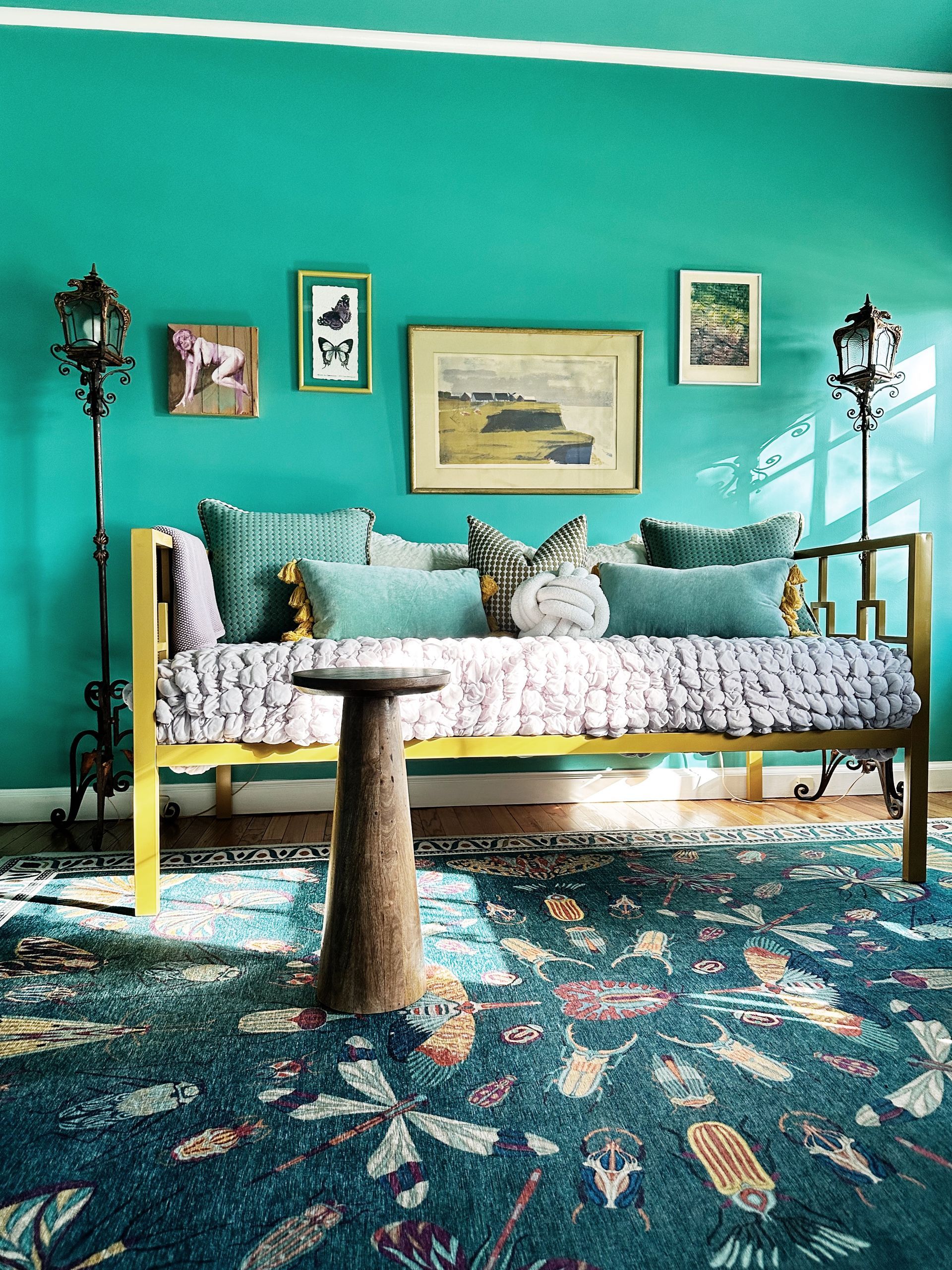 A living room with blue walls , a yellow couch , a rug , and a table.