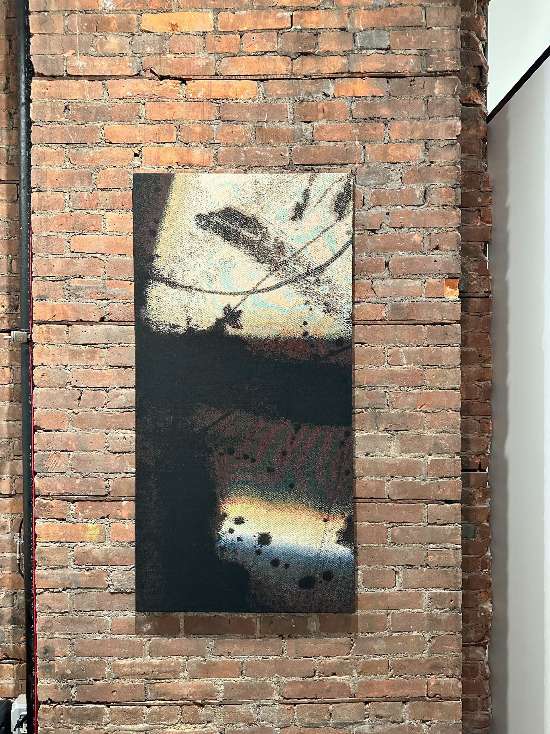 A large painting is hanging on a brick wall.