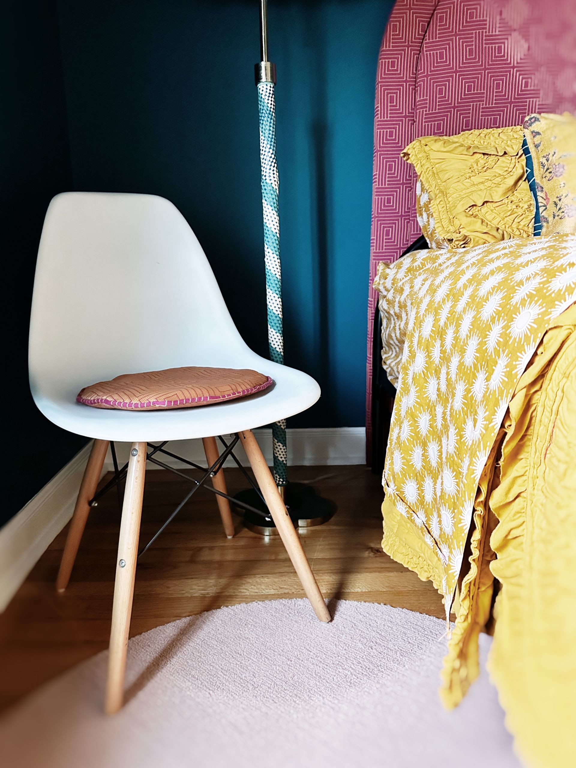 A white chair is sitting in a bedroom next to a bed.