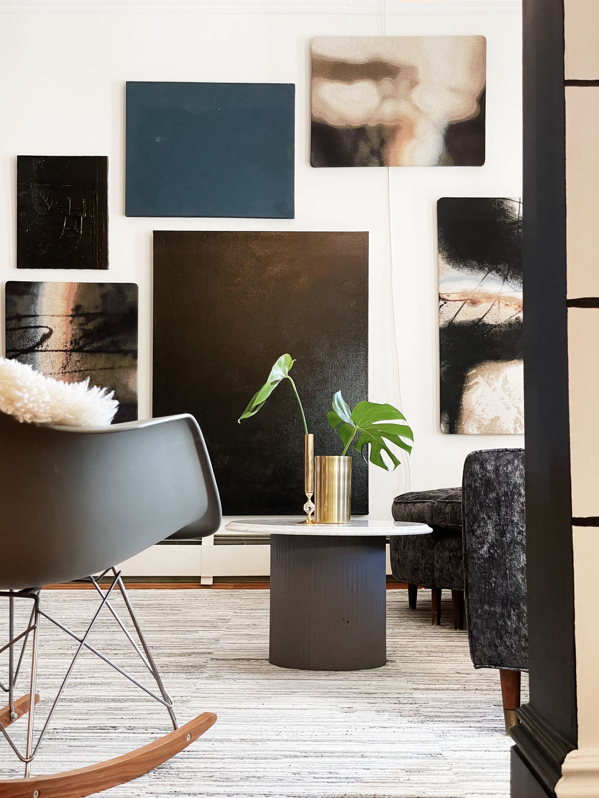 A rocking chair in a living room with paintings on the wall
