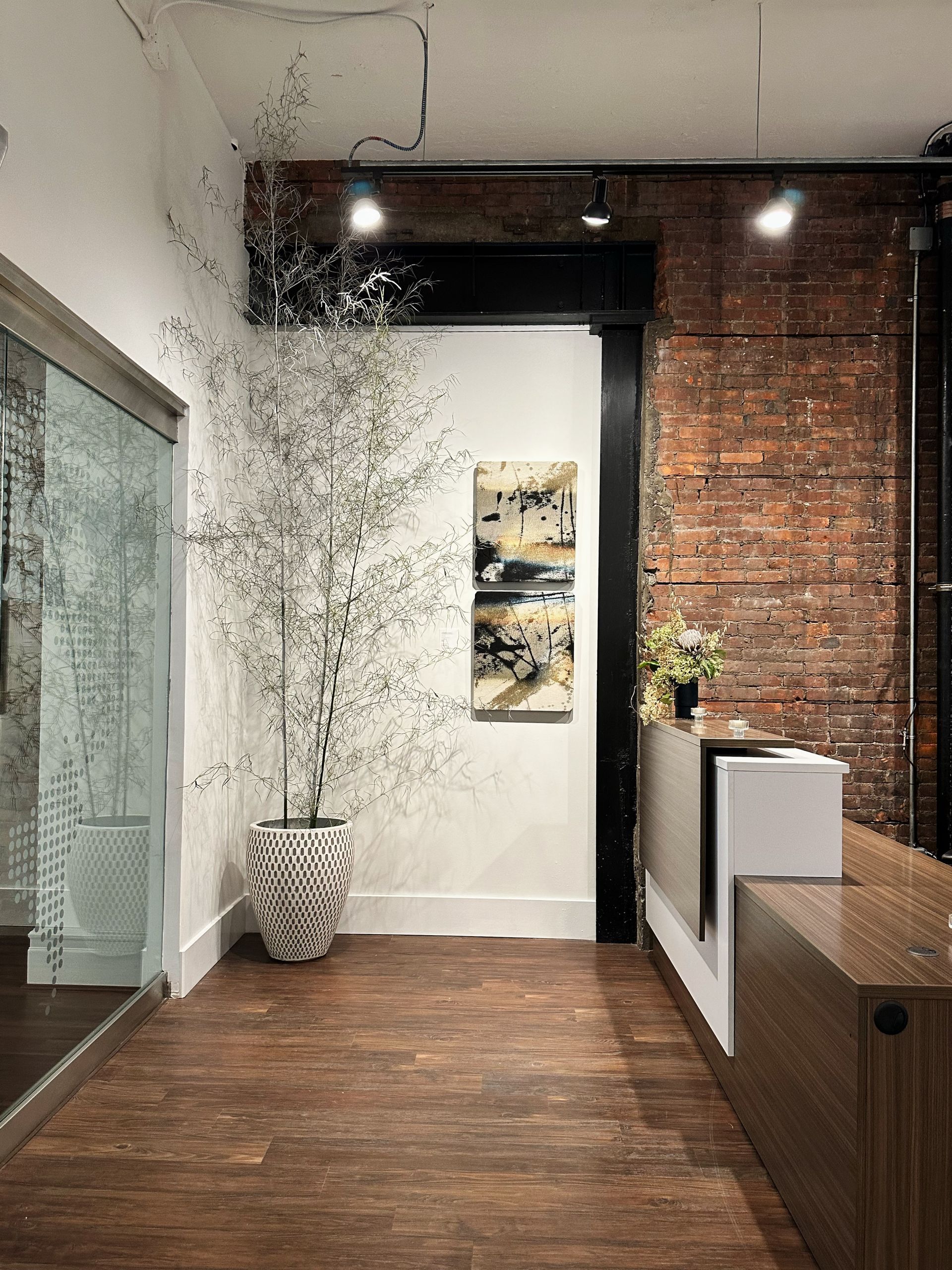 A long hallway with a brick wall and a white desk.