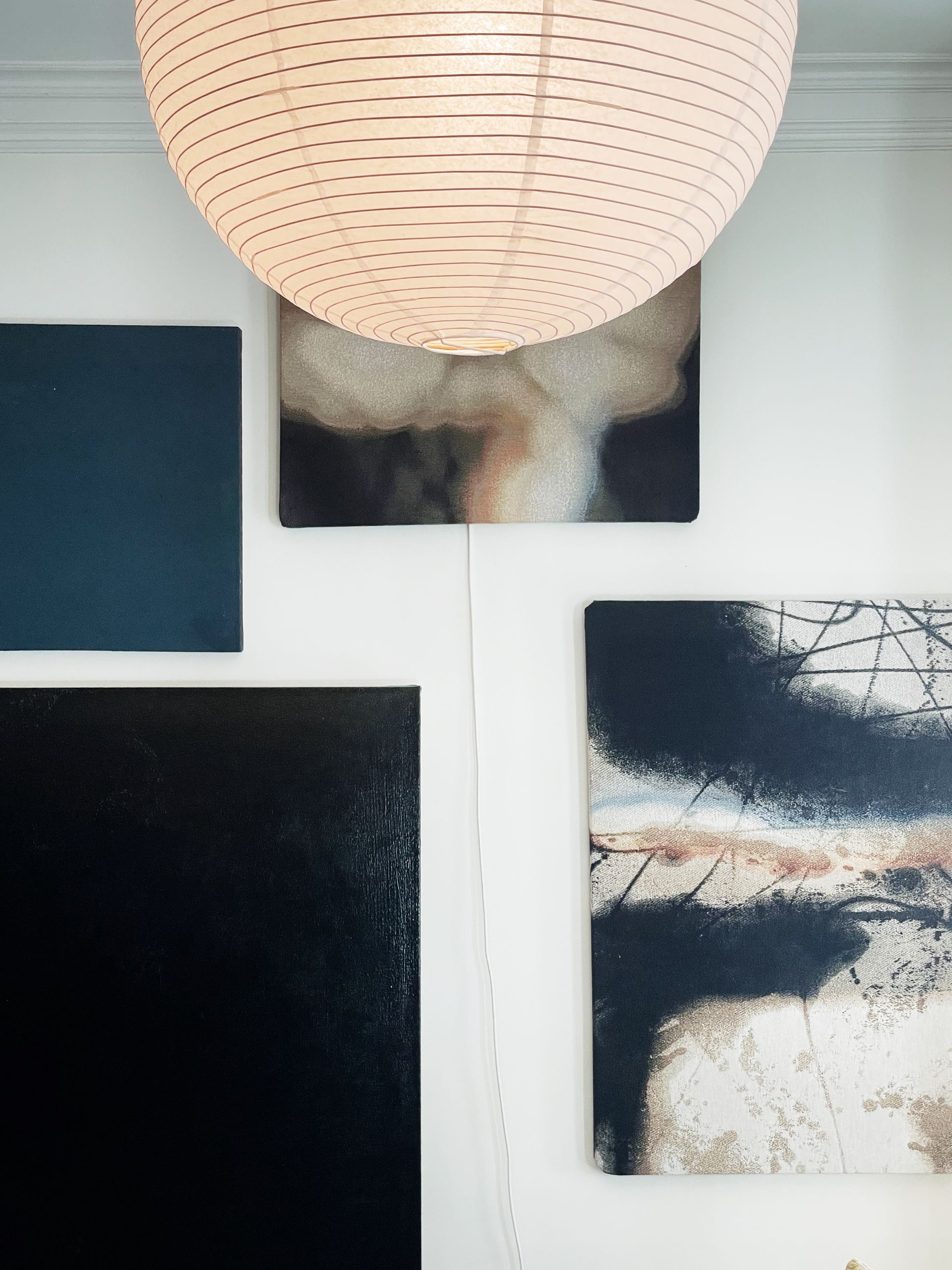 A lamp is hanging from the ceiling above a wall with paintings on it