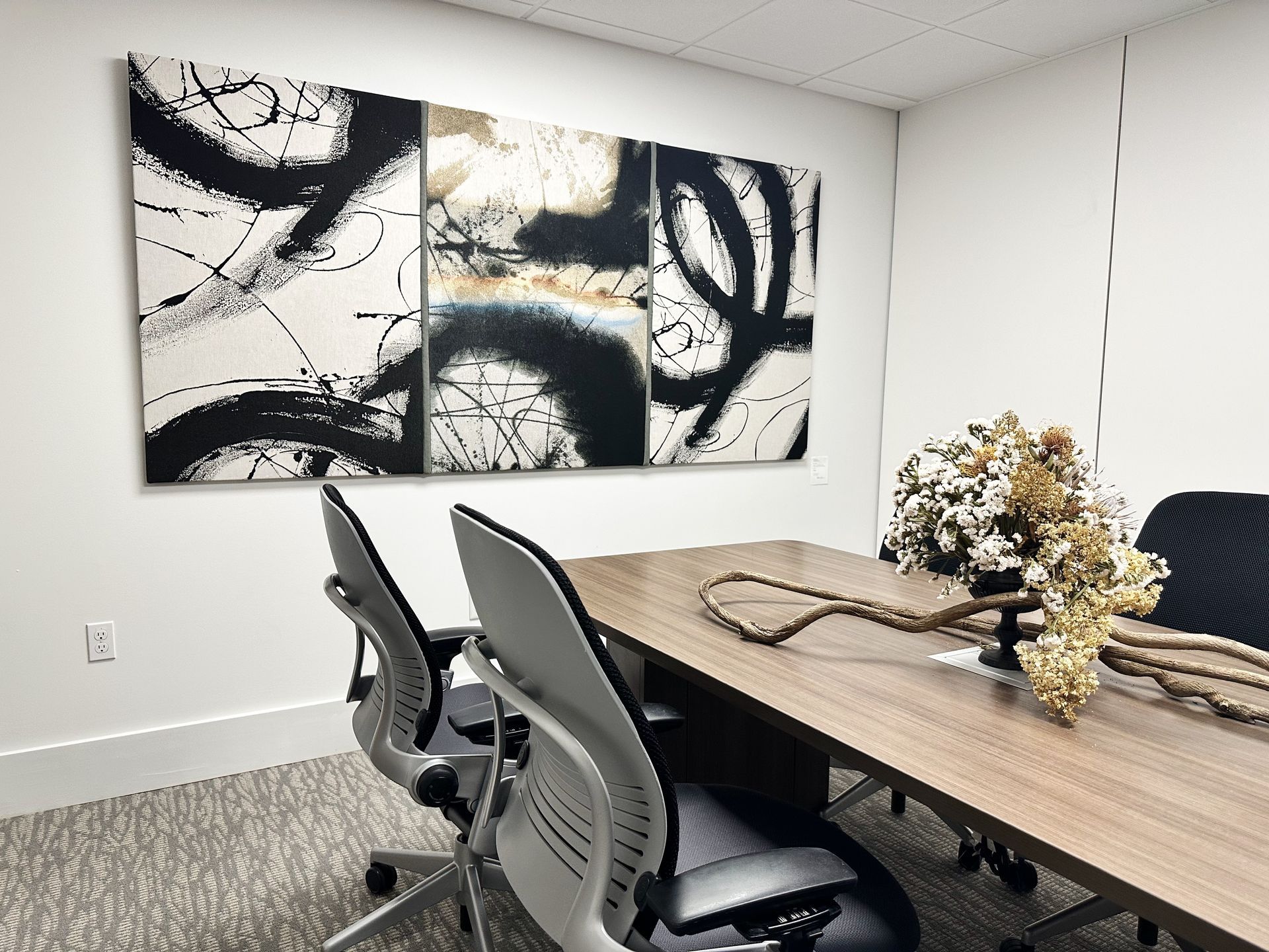 A conference room with a long table and chairs and a large painting on the wall.