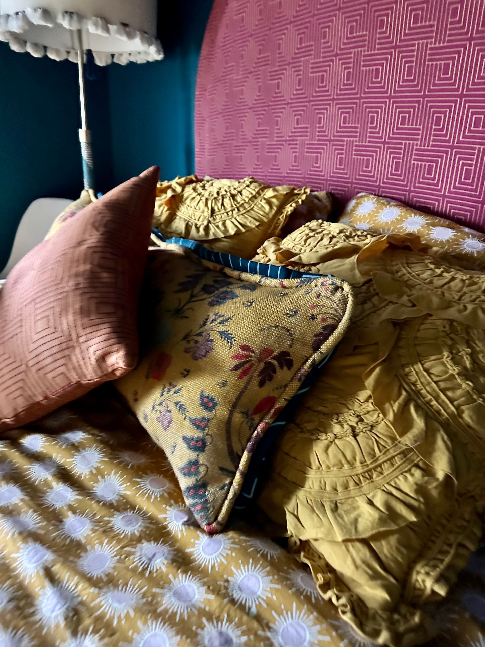 A bed with a pink headboard and pillows on it.