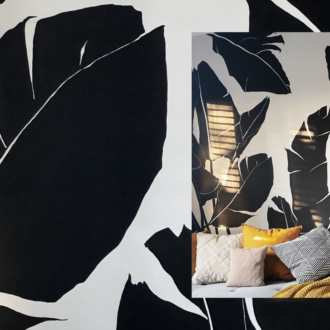 A bedroom with black and white leaves on the wall