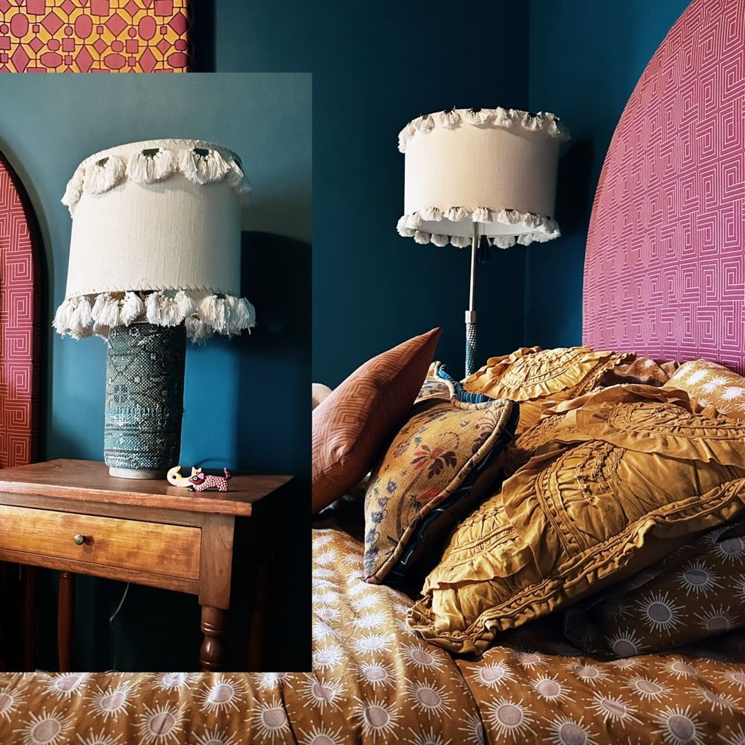 A bedroom with two lamps and a bed with a pink headboard