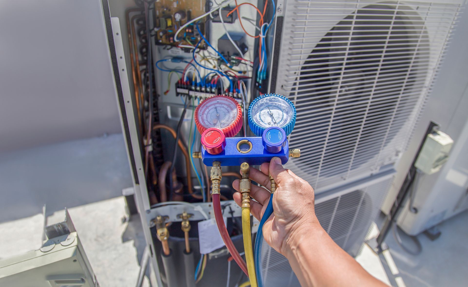 A person is working on an air conditioner with a gauge.