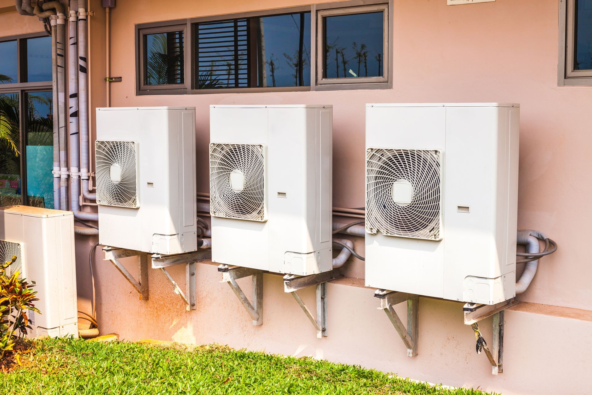 Three air conditioners are mounted on the side of a building.