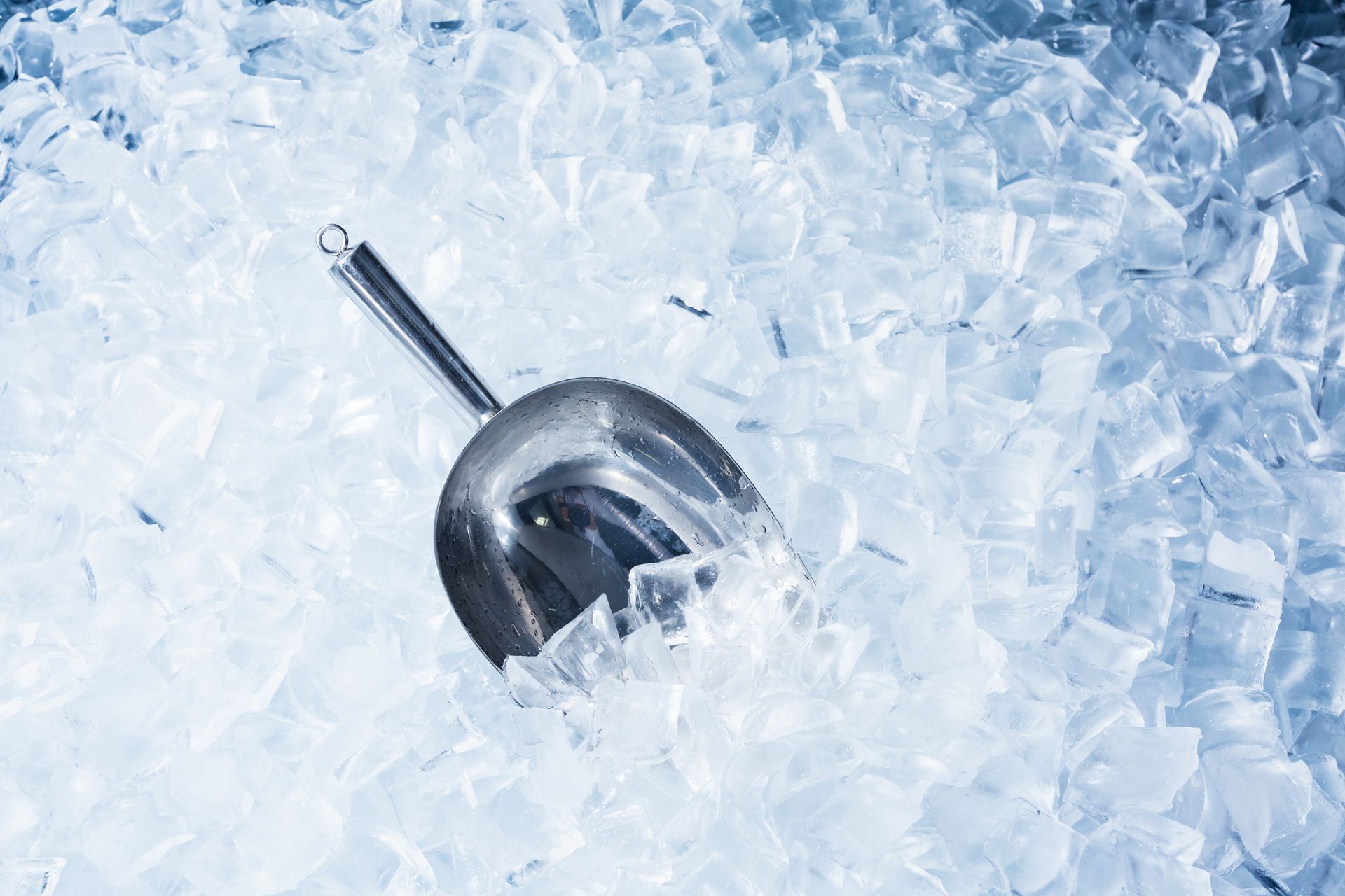 A scoop of ice is sitting on top of a pile of ice cubes.