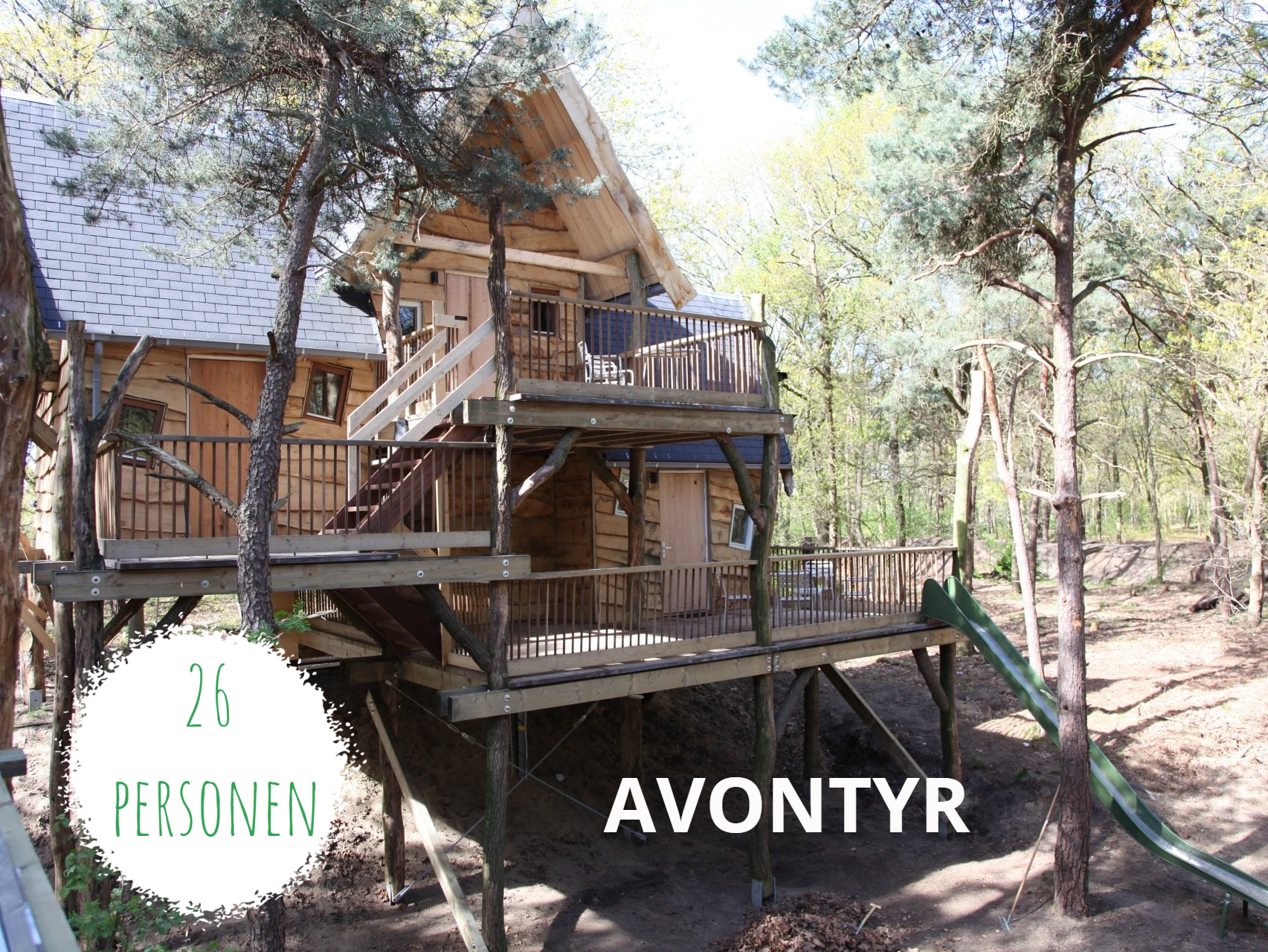 Groepsaccommodatie Avontyr Een houten boomhut met een balkon, een trap en een glijbaan in een bos, gemarkeerd met